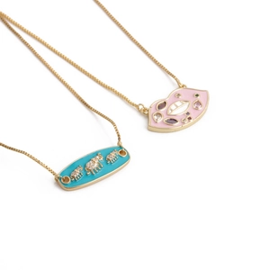 Gold necklaces featuring pink enamel lips and blue elephant pendants in diagonal layout