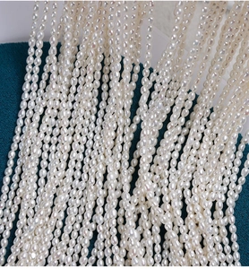 Macro shot of 2.5mm high-luster natural freshwater rice pearls on deep teal surface