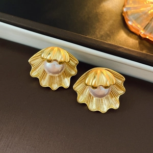 Detailed close-up of vintage shell-shaped earrings with gold metal and pink pearls