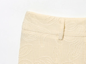 Détail du tissu en coton et lin crème avec broderie et passants de ceinture