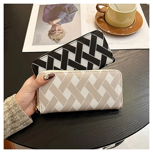 Detail shot of woven long zip wallets held in hand, featuring geometric textured patterns