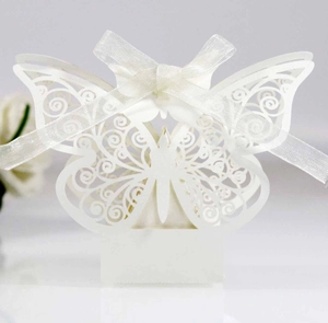 Macro shot of laser-cut butterfly wedding candy box in white with silk ribbon