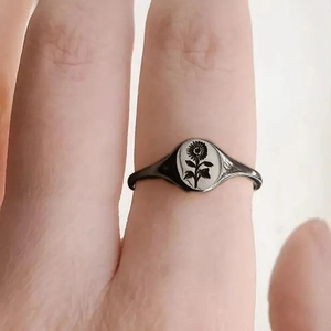 Close-up of a vintage sunflower signet ring with detailed floral engraving on silver band