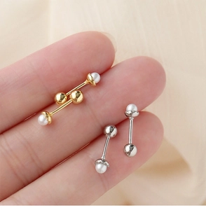 Detail of minimalist pearl screw-back stud earrings in gold and silver held in hand