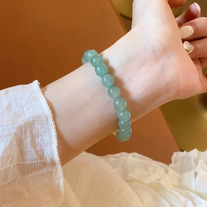 Detailed view of pale green aventurine beaded bracelet on a woman wrist with soft lighting