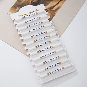 Detail of 14 white polymer clay bead bracelets with gold accents and CHEER letters
