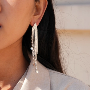 Gros plan sur des boucles d'oreilles à pompons argentés portées par un mannequin