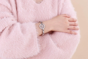 Detail of silver chain bracelet with hollow boy and girl silhouette charm on pink sweater