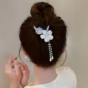 Dettaglio fermaglio con mughetto e nappe di perle su un elegante chignon alto