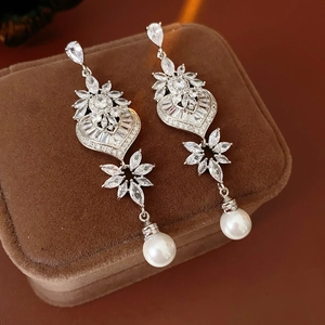 Detail of silver heart earrings with marquise crystals and elegant white pearl drops