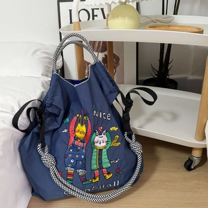 Detail shot of navy nylon drawstring bag featuring colorful cartoon animal embroidery