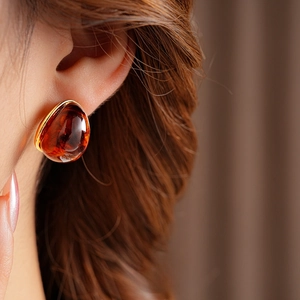 Detailed close-up of amber resin drop earrings in gold setting worn by a model