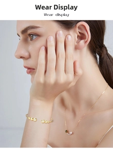 Elegante bracciale rigido dorato con gemme di moissanite indossato sul polso della modella