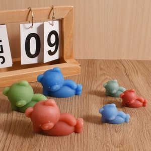 Sleeping bear silicone mold for scented candles shown in multiple colors on wooden desk