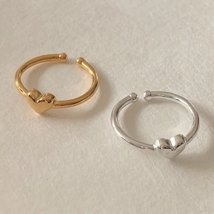 Close-up of minimalist gold and silver heart rings with adjustable open band design