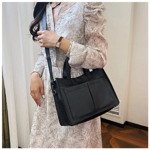 Side view of black PU leather tote bag with lychee texture and two functional front pockets