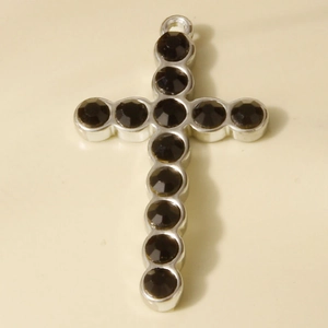 Detailed view of silver cross pendant with dark rhinestones for DIY jewelry making