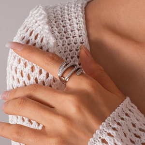 Silver multi-layer crossover ring with zircon stones worn by a model in soft light