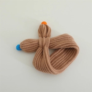 Detailed top view of brown knitted baby scarf with orange and blue pompom accents