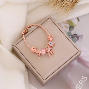 Detailed close-up of rose gold snake chain bracelet with pink glass beads and charms
