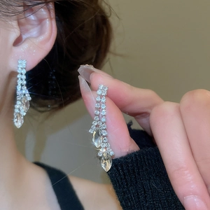 Detail of silver long tassel earrings with sparkling crystals and droplet pendants on model