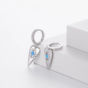 Macro detail of silver heart devil eye earrings with blue opal and sparkling crystals