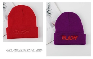 Detailed embroidery of RAW letters on knitted beanies in red and purple shades