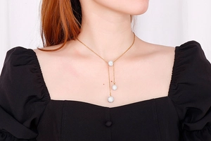Detailed view of women wearing a gold Y-shaped necklace with sparkling crystal ball charms