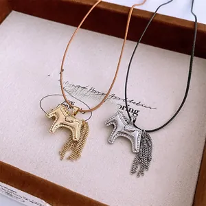 Detail of silver and gold pony pendant necklaces with metal tassels on a wooden display