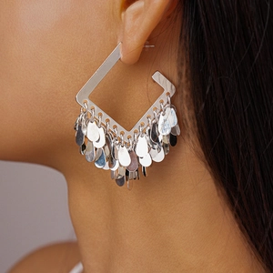 Detail shot of silver square tassel earrings with metallic sequin drops on a model