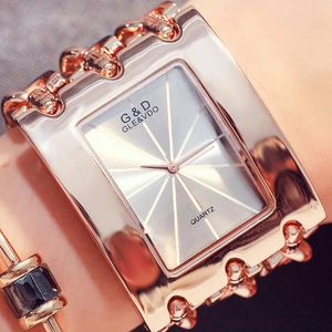 Close-up of a women's rose gold chain watch featuring a rectangular dial on the wrist
