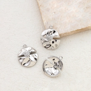 Detail of silver circular pendants with hammered texture and inset zircon heart accents