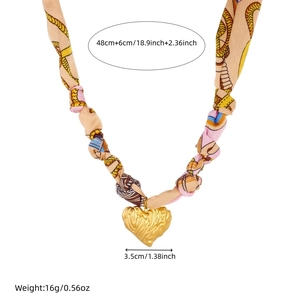 Detail view of printed silk ribbon necklace with a wavy gold heart-shaped pendant