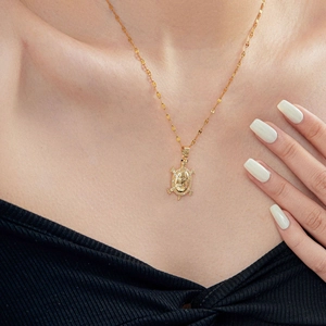 Close-up of gold turtle necklace with sparkling zirconia on a black sweater neck