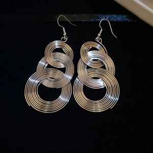 Close-up of silver circular tassel earrings with concentric rings on black velvet