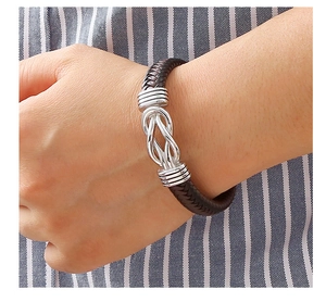 Detailed close-up of brown braided leather bracelet with silver knot buckle and metal clasp