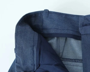 Detailed macro view of deep blue twill trousers showing internal waistband and stitching