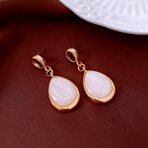 Detail of vintage gold teardrop earrings with pearlescent inlay on dark velvet background