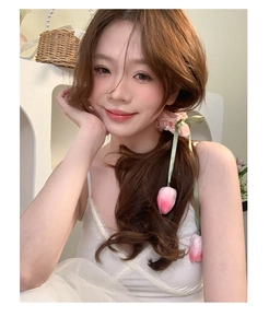 Detail of pink tulip hair clip with ribbon accessory worn on long hair with lace outfit