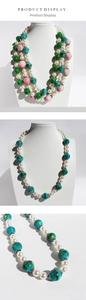 Detail of colorful beaded necklace with green cracked glass and pink floral pattern beads