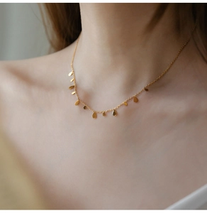 Close-up of golden titanium necklace with multiple small water drop pendants on female neck