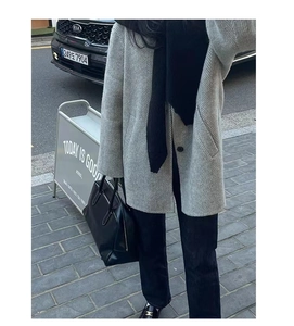Street style view of a grey herringbone wool coat paired with a black scarf and handbag