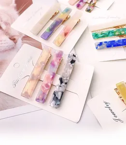 Close-up of three colorful acetate hair clips with marble patterns on a white card