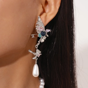Detailed view of ornate bird earrings with colorful crystals and teardrop pearl drops