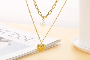 Détail d'un collier doré multicouche avec pendentif perle et cœur sur un magazine