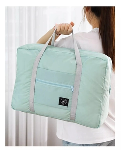 Close-up of a large mint green travel bag being carried by a model to show size
