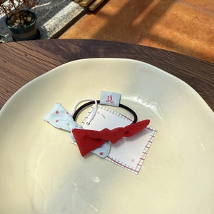 Close-up of a layered red and blue polka dot bow hair tie on a decorative cream plate