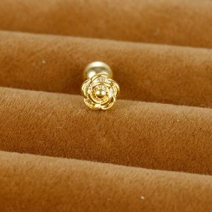 Gros plan d'un piercing d'oreille fleur de rose dorée avec fermoir à vis sur velours