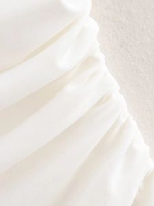Makro-Detail des gerafften weißen Satinstoffs an einem ärmellosen Sommerkleid