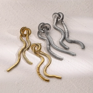 Detailed macro view of 16k gold and silver snake bone chain tassel knot earrings